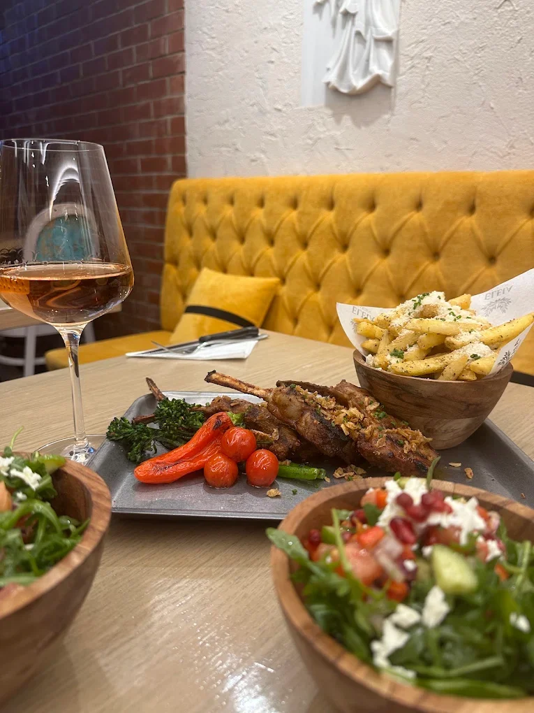 Lamb chops, salads and fries with a glass of rosé by the yellow velvet booth